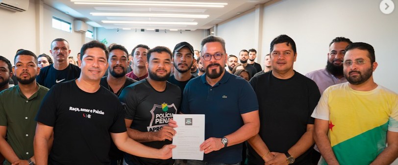 Dr. Junior Nascimento assinando documento de compromisso ao lado de servidores da Polícia Penal